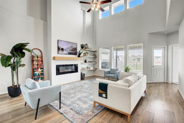 930 Blue Oak Blvd, San Marcos, TX 78666 - living room with a high ceiling, ceiling fan, wood finished floors, a glass covered fireplace, and baseboards