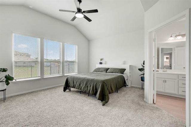 bedroom with vaulted ceiling, light carpet, connected bathroom, and baseboards
