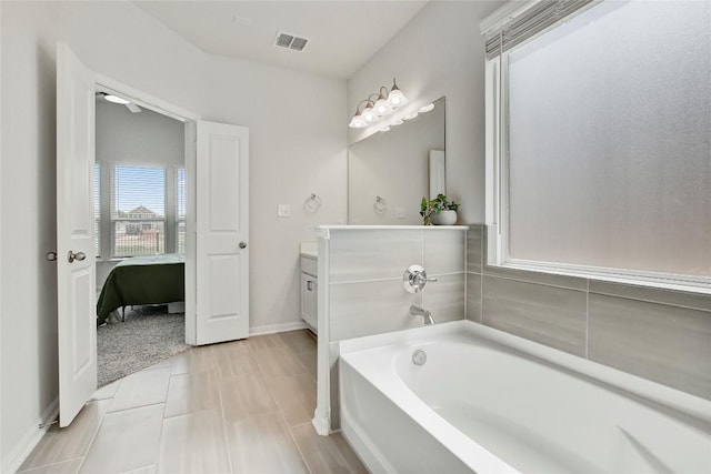 full bath featuring vanity, baseboards, a bath, and visible vents