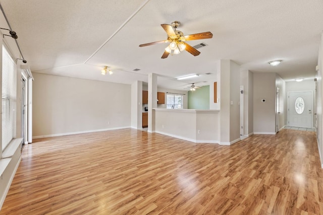 unfurnished living room with a ceiling fan, light wood finished floors, baseboards, and a textured ceiling