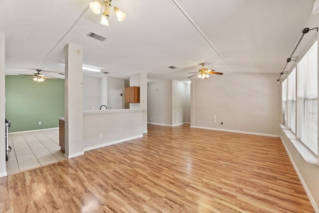 unfurnished living room featuring a ceiling fan, light wood-type flooring, and baseboards