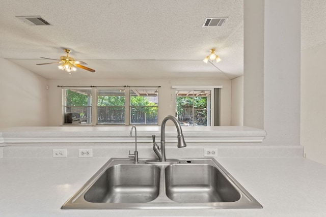 kitchen with a sink, a textured ceiling, light countertops, and ceiling fan
