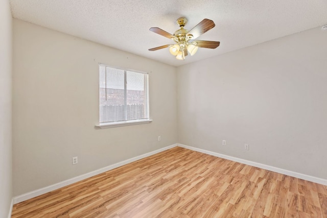 spare room featuring wood finished floors, baseboards, a ceiling fan, and a textured ceiling