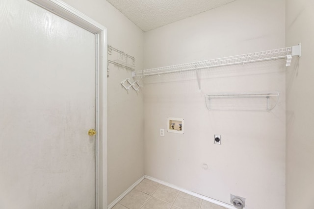 laundry area featuring electric dryer hookup, washer hookup, light tile patterned flooring, and baseboards