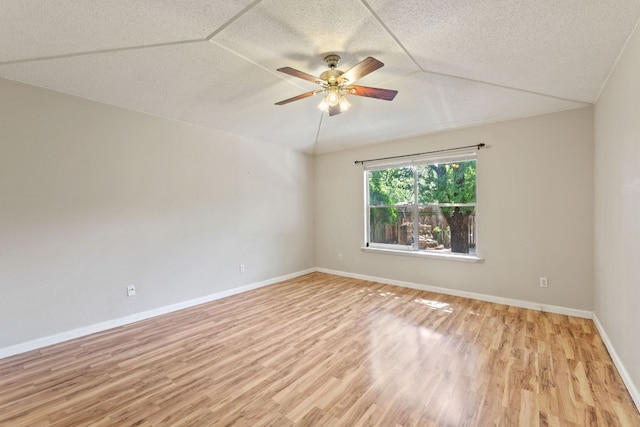 unfurnished room with light wood-style flooring, ceiling fan, baseboards, a textured ceiling, and lofted ceiling