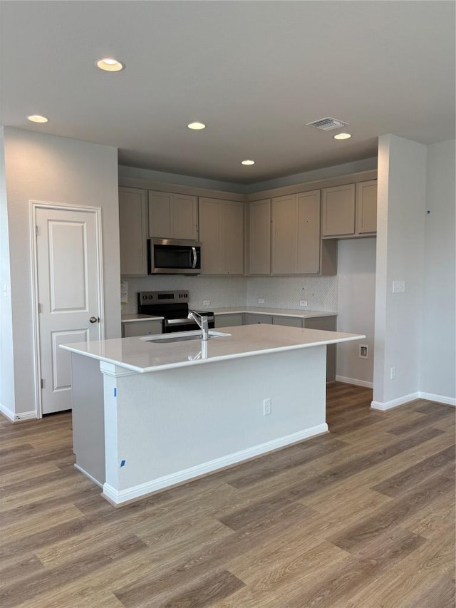 108 Elm Branch Trl, Taylor, TX 76574 - kitchen featuring stainless steel microwave, electric range, gray cabinetry, a kitchen island with sink, and recessed lighting