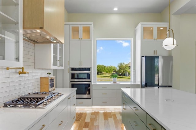 17109 Saint Therese Rd, Manor, TX 78653 - kitchen featuring stainless steel appliances, wall chimney range hood, backsplash, light wood-style floors, and recessed lighting