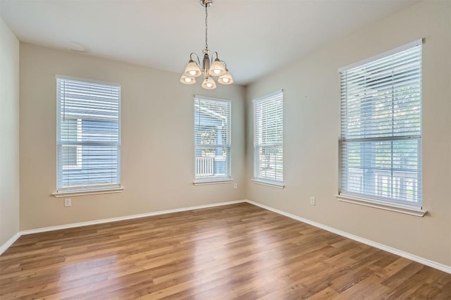 unfurnished room with a chandelier, baseboards, and wood finished floors