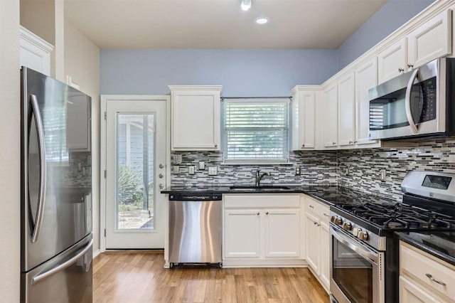 kitchen with backsplash, appliances with stainless steel finishes, light wood-style flooring, and a sink