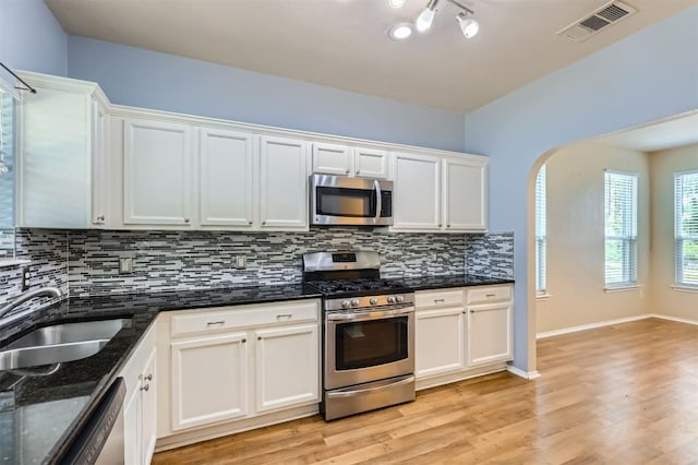 kitchen with a sink, stainless steel appliances, visible vents, backsplash, and light wood-style floors