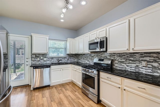 kitchen with light wood finished floors, backsplash, appliances with stainless steel finishes, and a sink