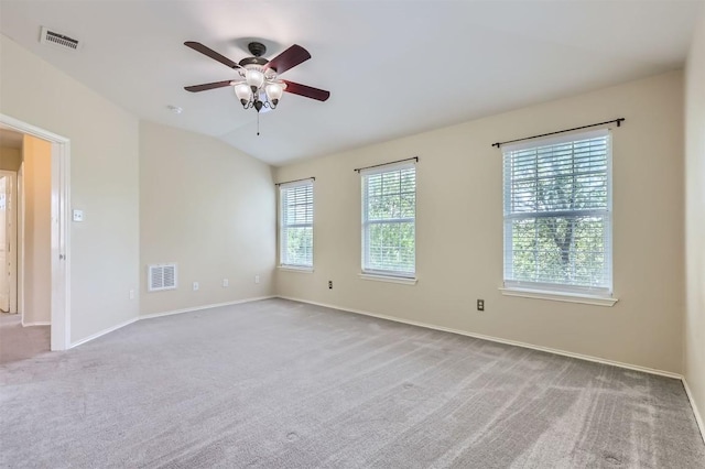 carpeted spare room featuring vaulted ceiling, baseboards, a ceiling fan, and visible vents