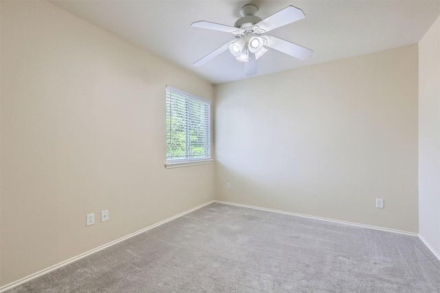 carpeted spare room featuring baseboards and a ceiling fan