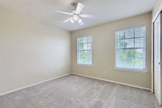 carpeted empty room featuring baseboards and a ceiling fan