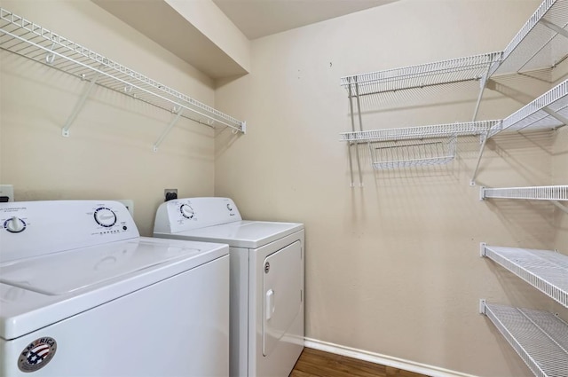 laundry area featuring baseboards, laundry area, wood finished floors, and washer and clothes dryer