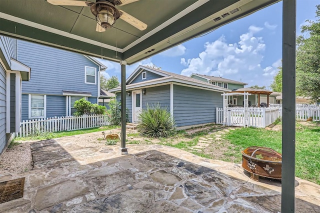view of patio / terrace featuring ceiling fan, fence, and a fire pit