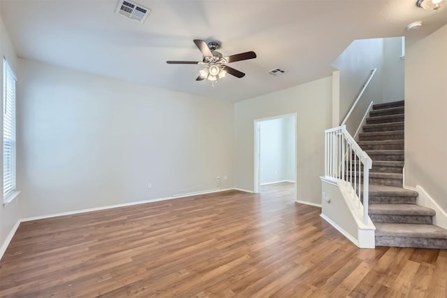 empty room with stairway, visible vents, and wood finished floors