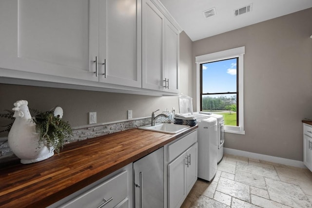 washroom featuring cabinet space, washing machine and dryer, visible vents, and baseboards