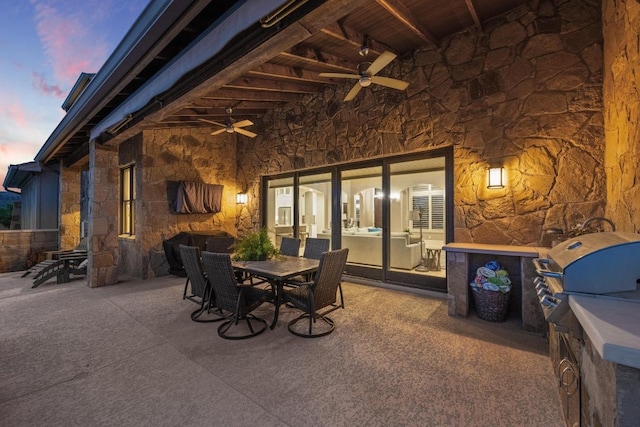 patio terrace at dusk with outdoor dining space, area for grilling, and a ceiling fan