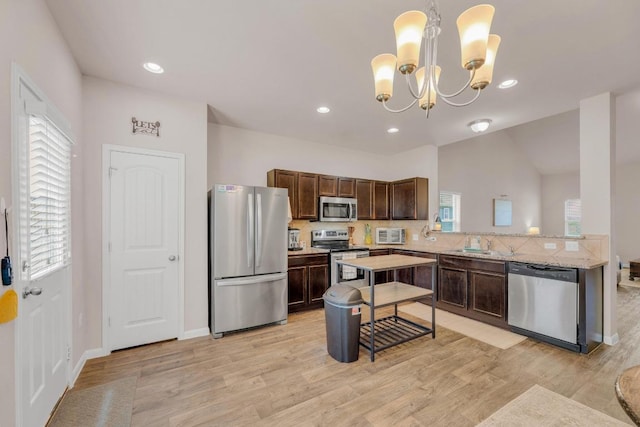 310 Garcitas Creek Ln, Hutto, TX 78634 - kitchen featuring appliances with stainless steel finishes, light wood-style flooring, a sink, a chandelier, and backsplash