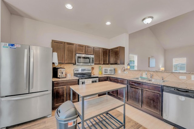 310 Garcitas Creek Ln, Hutto, TX 78634 - kitchen featuring stainless steel appliances, a sink, light wood-style floors, dark brown cabinetry, and backsplash