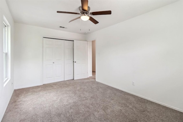 unfurnished bedroom featuring a closet, baseboards, ceiling fan, visible vents, and carpet floors