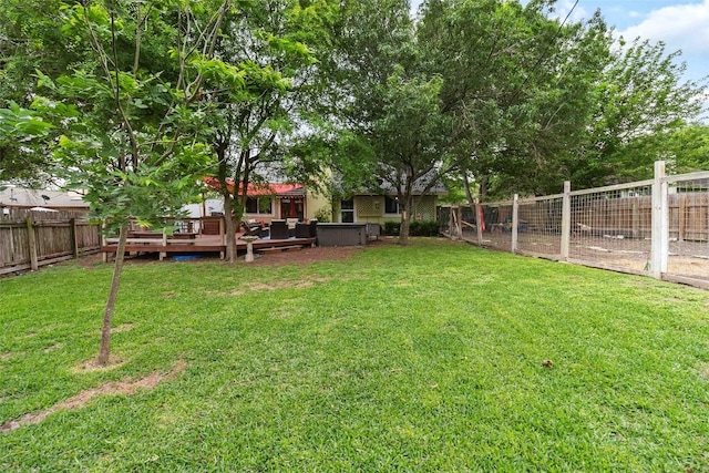 view of yard with a fenced backyard, a wooden deck, and a hot tub