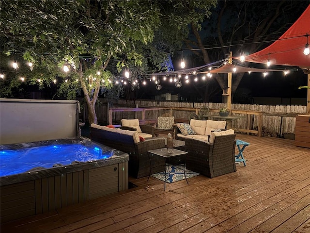 deck at night featuring a hot tub, a fenced backyard, and an outdoor living space