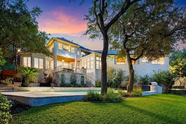 2901 Meandering River Ct, Austin, TX 78746 - back of property at dusk featuring a yard, roof mounted solar panels, stairway, and stone siding