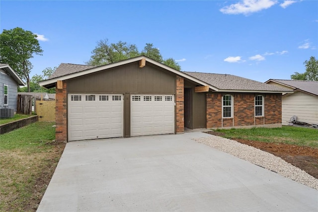 ranch-style home with driveway, fence, an attached garage, a shingled roof, and a front lawn
