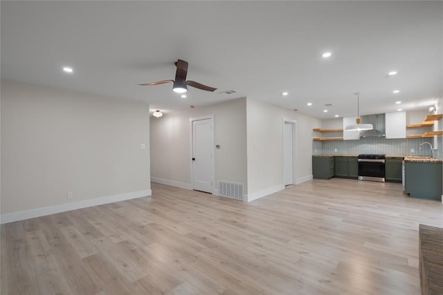 unfurnished living room with a sink, visible vents, recessed lighting, a ceiling fan, and baseboards