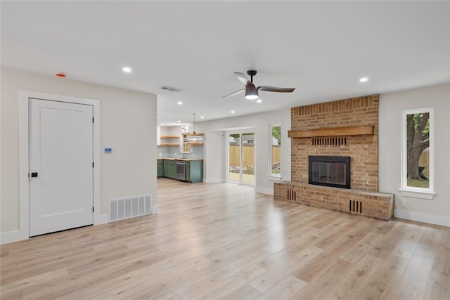 unfurnished living room featuring a healthy amount of sunlight, a ceiling fan, and visible vents
