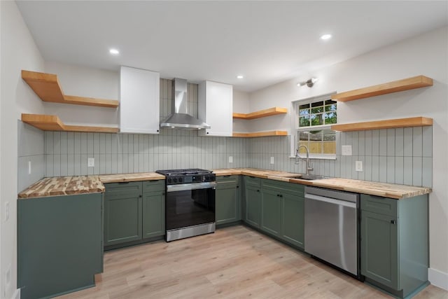 kitchen with open shelves, green cabinetry, and wall chimney exhaust hood