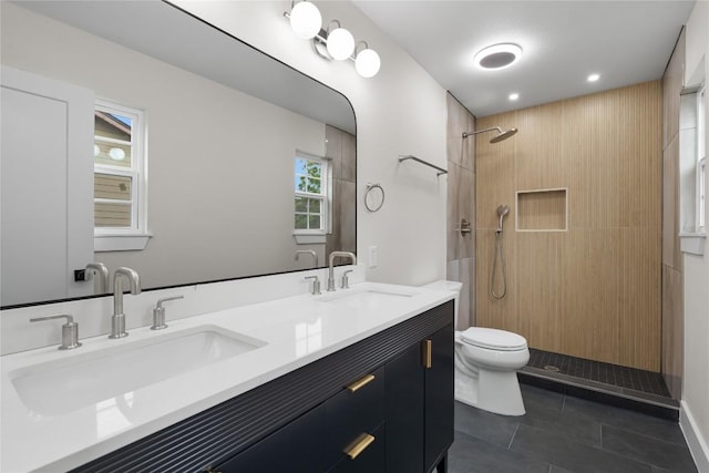bathroom with toilet, tile patterned flooring, tiled shower, and a sink