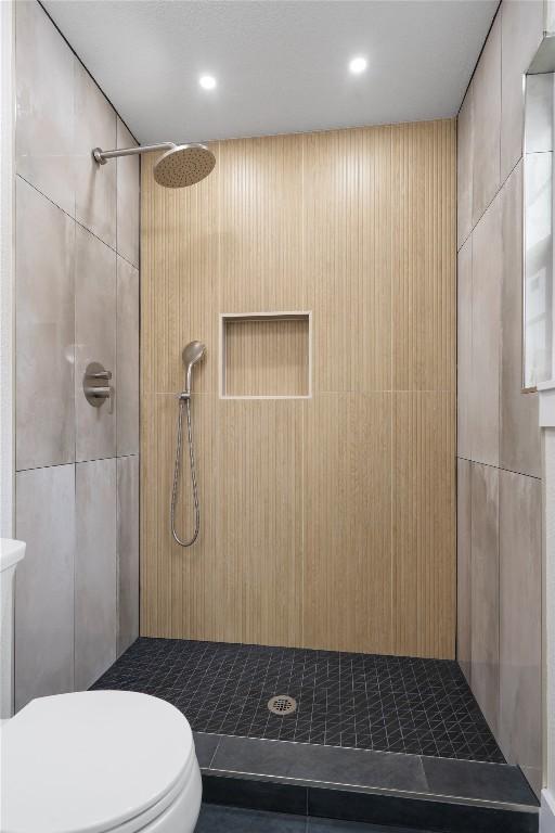 bathroom featuring toilet and a tile shower