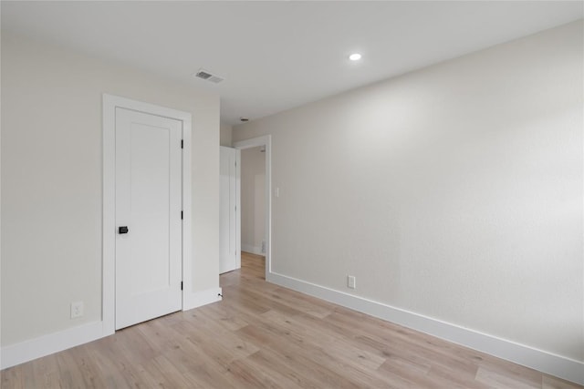 spare room featuring light wood finished floors, visible vents, and baseboards