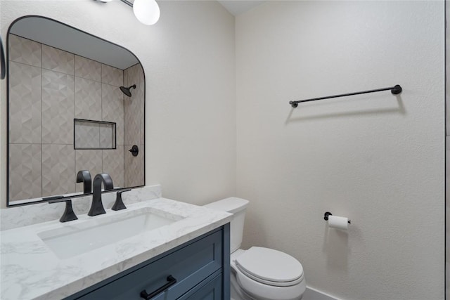 bathroom with toilet, vanity, and a tile shower