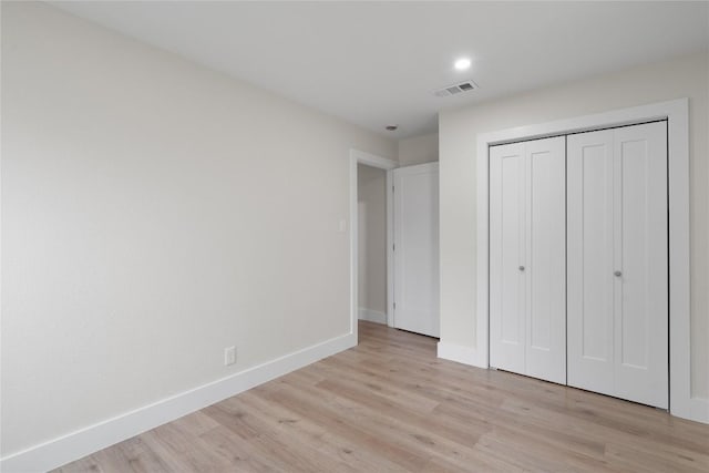 unfurnished bedroom featuring a closet, light wood-style floors, visible vents, and baseboards