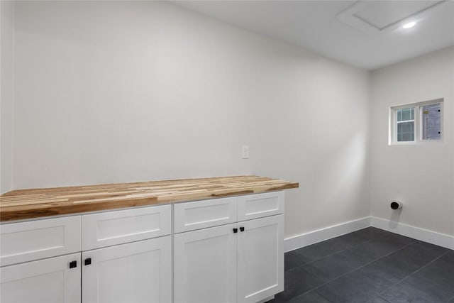 laundry area featuring baseboards, attic access, and dark tile patterned floors