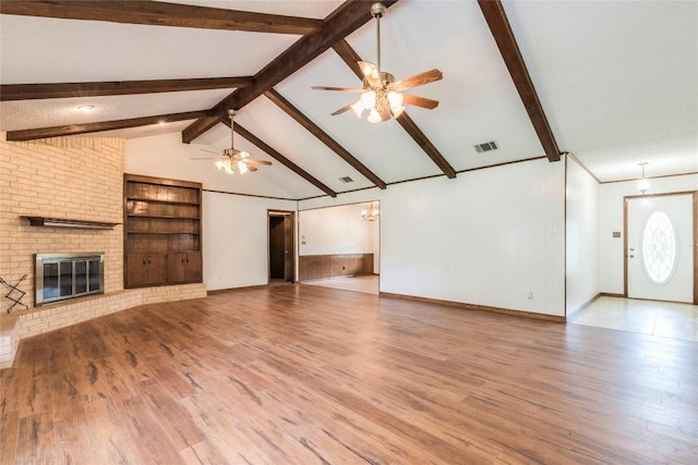 13505 Broadmeade Ave, Austin, TX 78729 - unfurnished living room featuring a ceiling fan, a brick fireplace, wood finished floors, and a chandelier