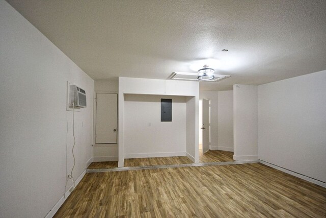 2539 Fayette Dr, New Braunfels, TX 78130 - unfurnished room featuring electric panel, a wall mounted air conditioner, wood finished floors, baseboards, and a textured ceiling