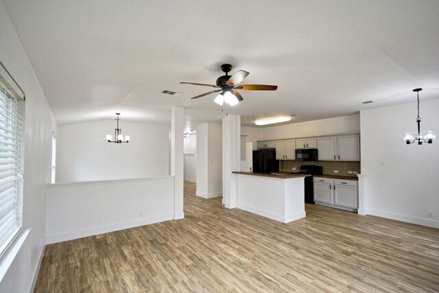 2539 Fayette Dr, New Braunfels, TX 78130 - kitchen with a chandelier, dark countertops, black appliances, light wood-style flooring, and plenty of natural light