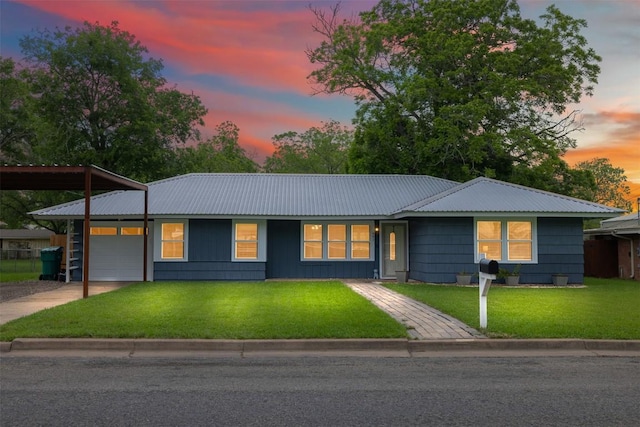 single story home featuring a lawn, metal roof, driveway, and a garage