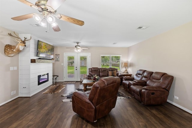 living room with a large fireplace, ceiling fan, visible vents, and wood finished floors