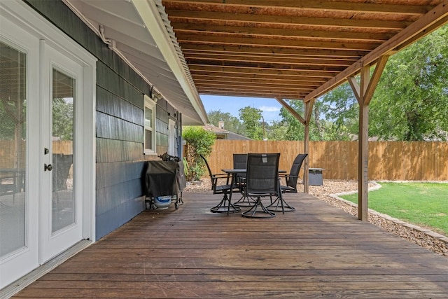 wooden terrace with outdoor dining area, fence, and a grill