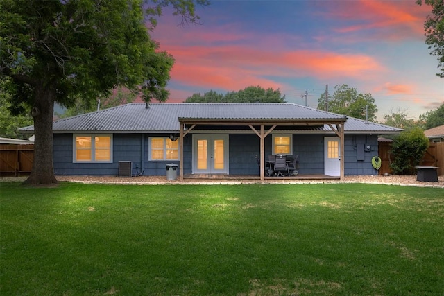 rear view of house with fence, french doors, and a lawn