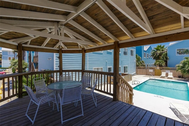 wooden terrace with outdoor dining area, fence, a community pool, and a patio area