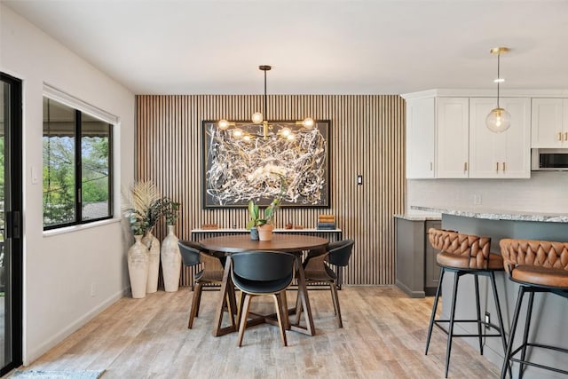 113 Comet, Lakeway, TX 78734 - dining space with baseboards, light wood-style flooring, a chandelier, and an accent wall