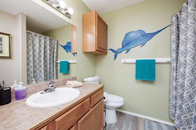 bathroom with toilet, wood finished floors, and vanity