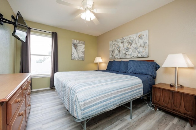 bedroom with light wood finished floors, baseboards, and ceiling fan